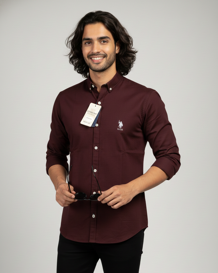 Man wearing a maroon shirt with a brand tag on a gray background
